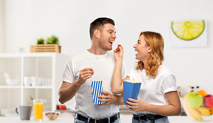 Image showing happy couple in white t-shirts eating popcorn