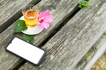 Image showing Mallow tea with smartphone on old wooden background