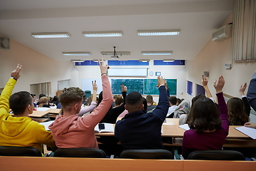 Image showing Raised hands and arms of large group of people in class room