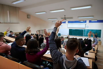 Image showing Raised hands and arms of large group of people in class room