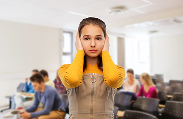 Image showing student girl closing ears by hands at school