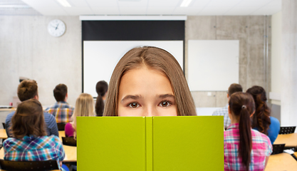 Image showing teenage student girl hiding over book at school