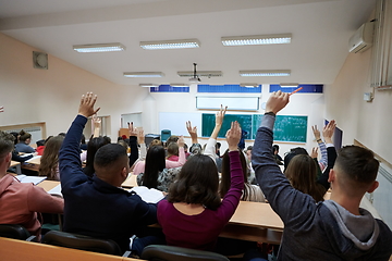 Image showing Raised hands and arms of large group of people in class room