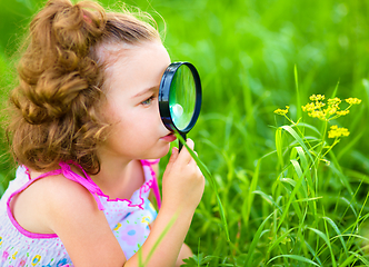 Image showing Young girl is looking at flower through magnifier