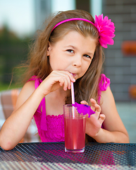 Image showing Little girl is drinking cherry juice