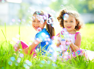 Image showing Two little girls are blowing soap bubbles