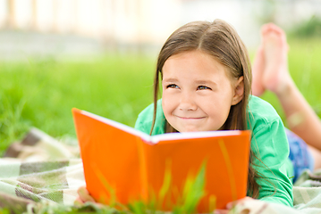 Image showing Little girl is reading a book outdoors