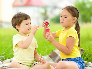 Image showing Little girl and boy are blowing soap bubbles