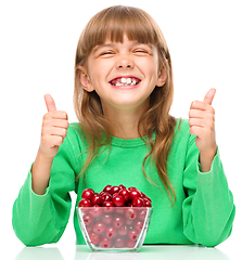 Image showing Cute girl is eating cherries showing thumb up sigh