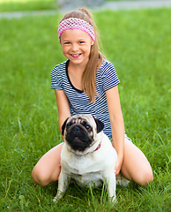 Image showing Little girl and her pug dog on green grass