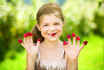 Image showing Young girl is holding raspberries on her fingers