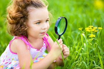 Image showing Young girl is looking at flower through magnifier