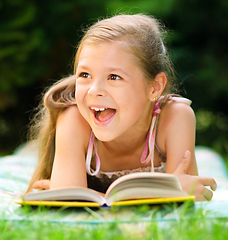 Image showing Little girl is reading a book outdoors