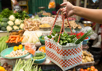 Image showing Hand holding basket with vegetable in wet market 