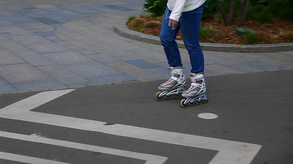 Image showing Feet of girl riding on a roller skates ride on asphalt.