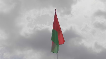 Image showing Belarus flag on the flagpole waving in the wind against a blue sky with clouds. Slow motion