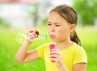 Image showing Little girl is blowing a soap bubbles