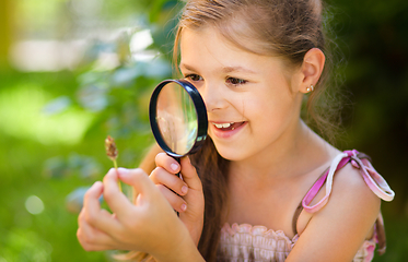 Image showing Young girl is looking at flower through magnifier