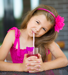 Image showing Little girl is drinking cherry juice