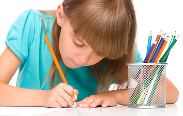 Image showing Little girl is drawing using pencils