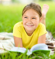 Image showing Little girl is reading a book outdoors