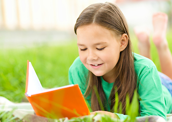 Image showing Little girl is reading a book outdoors