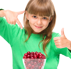 Image showing Cute girl is eating cherries showing thumb up sigh