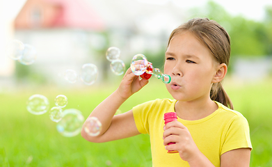 Image showing Little girl is blowing a soap bubbles