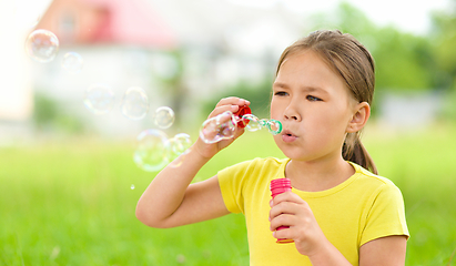 Image showing Little girl is blowing a soap bubbles