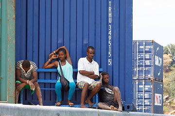 Image showing Malagasy peoples resting in the shadow of the containers in Nosy