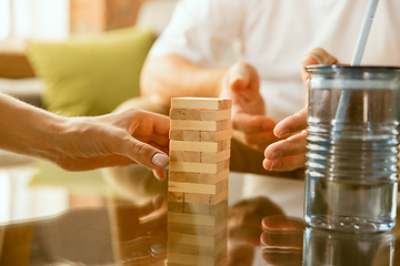 Image showing Close up of senior man\'s hands doing his wooden constructor at home - concept of home studying