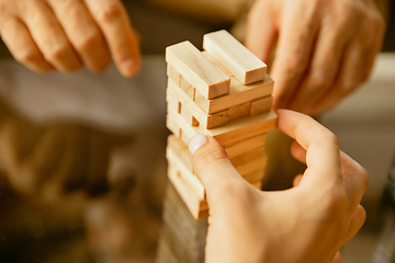 Image showing Close up of senior man\'s hands doing his wooden constructor at home - concept of home studying