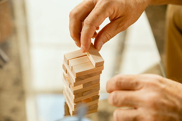 Image showing Close up of senior man\'s hands doing his wooden constructor at home - concept of home studying