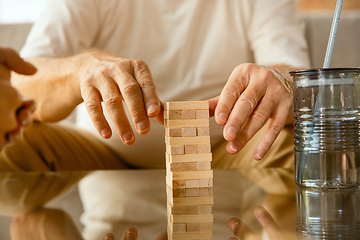 Image showing Close up of senior man\'s hands doing his wooden constructor at home - concept of home studying