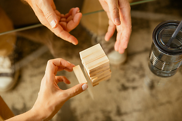 Image showing Close up of senior man\'s hands doing his wooden constructor at home - concept of home studying