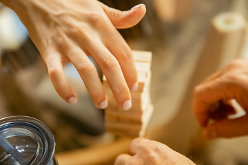 Image showing Close up of senior man\'s hands doing his wooden constructor at home - concept of home studying