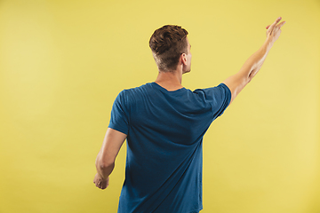 Image showing Caucasian young man\'s half-length portrait on yellow background