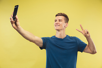 Image showing Caucasian young man\'s half-length portrait on yellow background