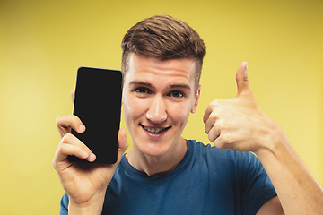 Image showing Caucasian young man\'s half-length portrait on yellow background