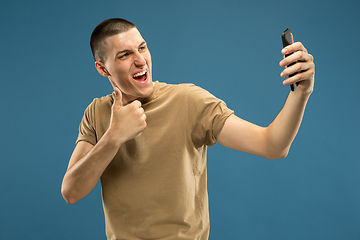 Image showing Caucasian young man\'s half-length portrait on blue background