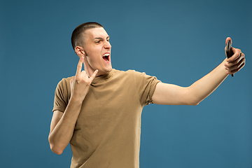 Image showing Caucasian young man\'s half-length portrait on blue background