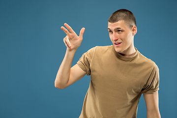 Image showing Caucasian young man\'s half-length portrait on blue background