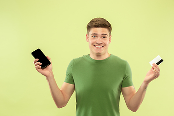 Image showing Caucasian young man\'s half-length portrait on green background