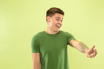 Image showing Caucasian young man\'s half-length portrait on green background