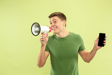 Image showing Caucasian young man\'s half-length portrait on green background