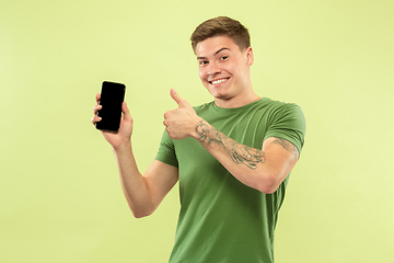 Image showing Caucasian young man\'s half-length portrait on green background