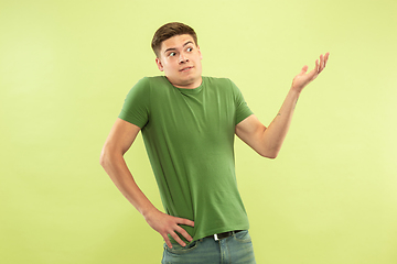 Image showing Caucasian young man\'s half-length portrait on green background