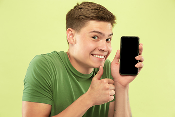 Image showing Caucasian young man\'s half-length portrait on green background