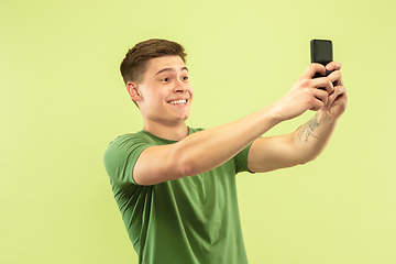 Image showing Caucasian young man\'s half-length portrait on green background