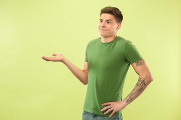 Image showing Caucasian young man\'s half-length portrait on green background